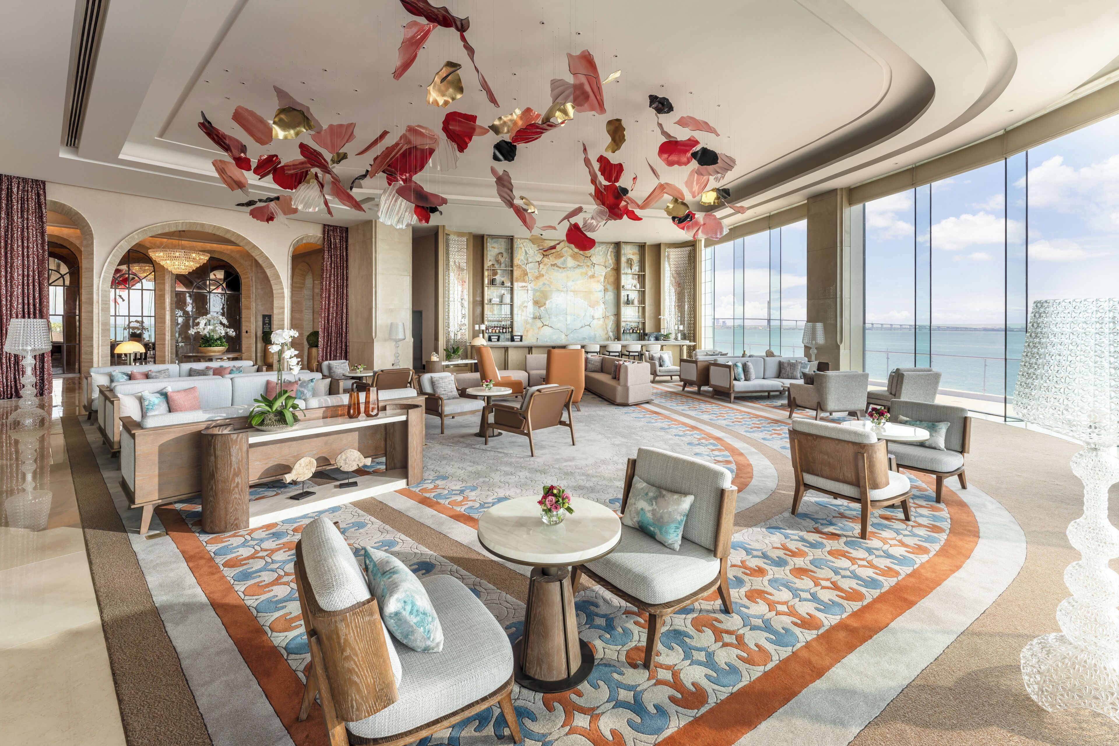 A spacious lobby with a large seating area, a bar, and a view of the sea.