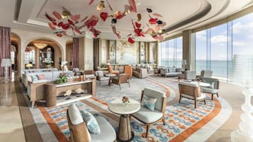 A spacious lobby with a large seating area, a bar, and a view of the sea.