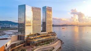 A modern hotel with two tall glass buildings, a waterfront promenade, and a bridge in the background. - NUSTAR Hotel Cebu (Cebu City)