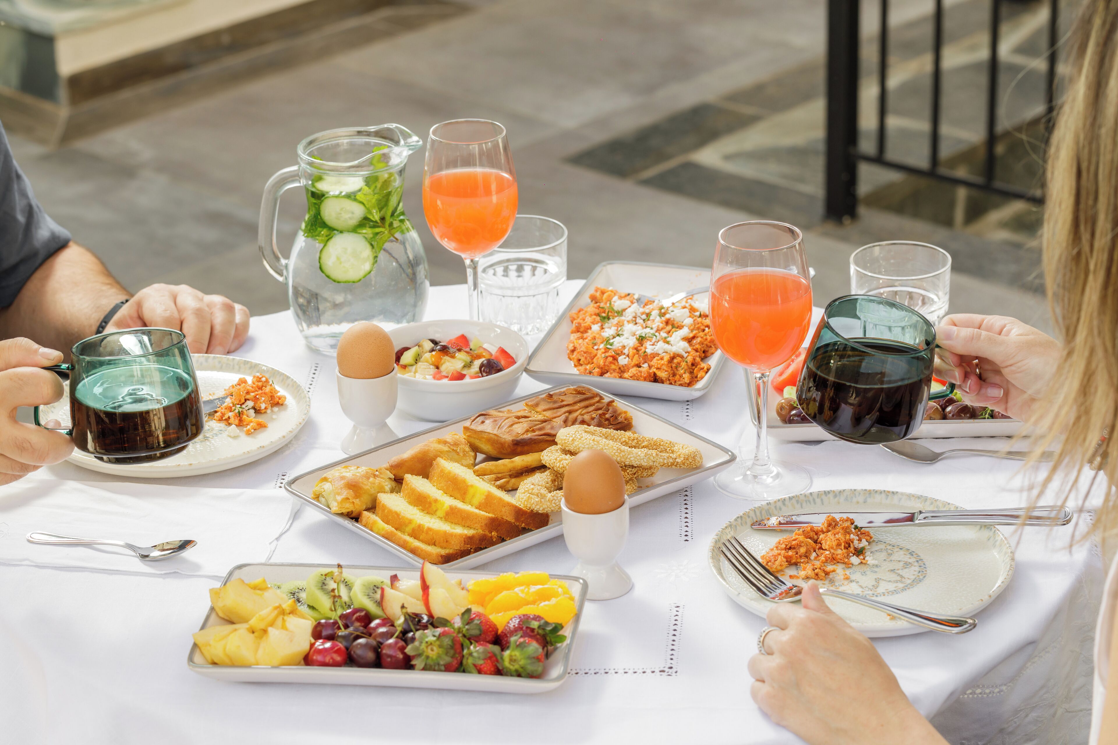 Una mesa lista para el desayuno con diversos platos, bebidas y utensilios.
