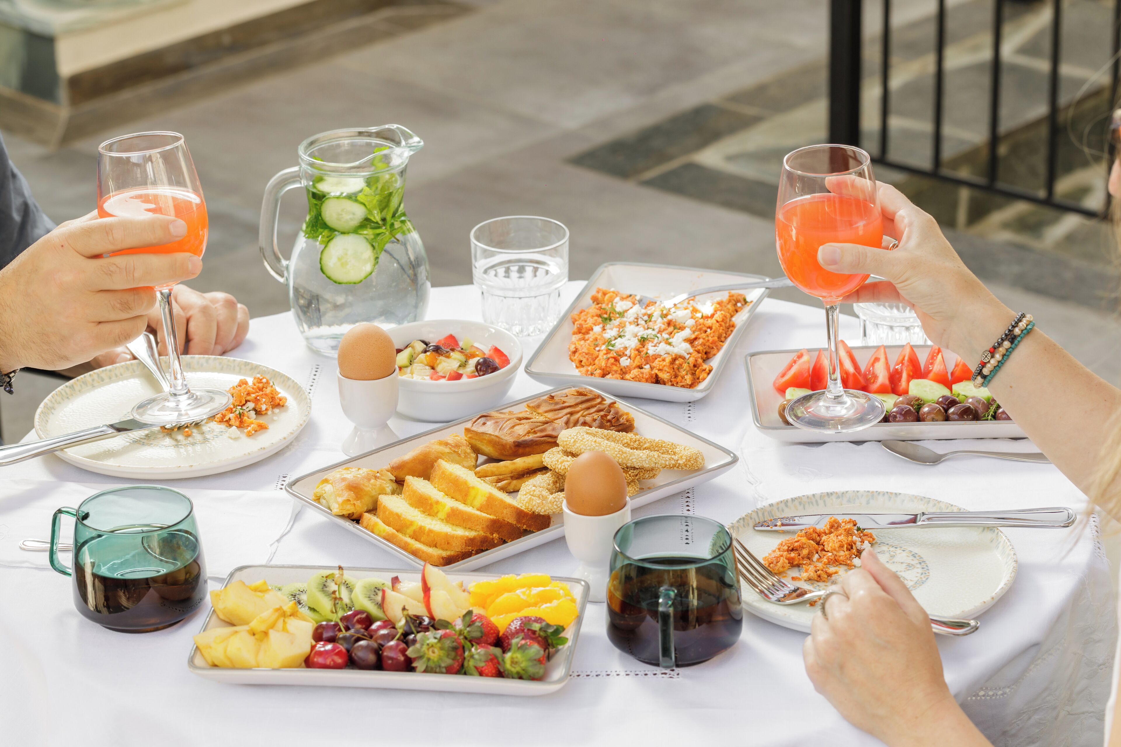 Una mesa preparada con diversos alimentos para el desayuno, como frutas, pasteles y bebidas.