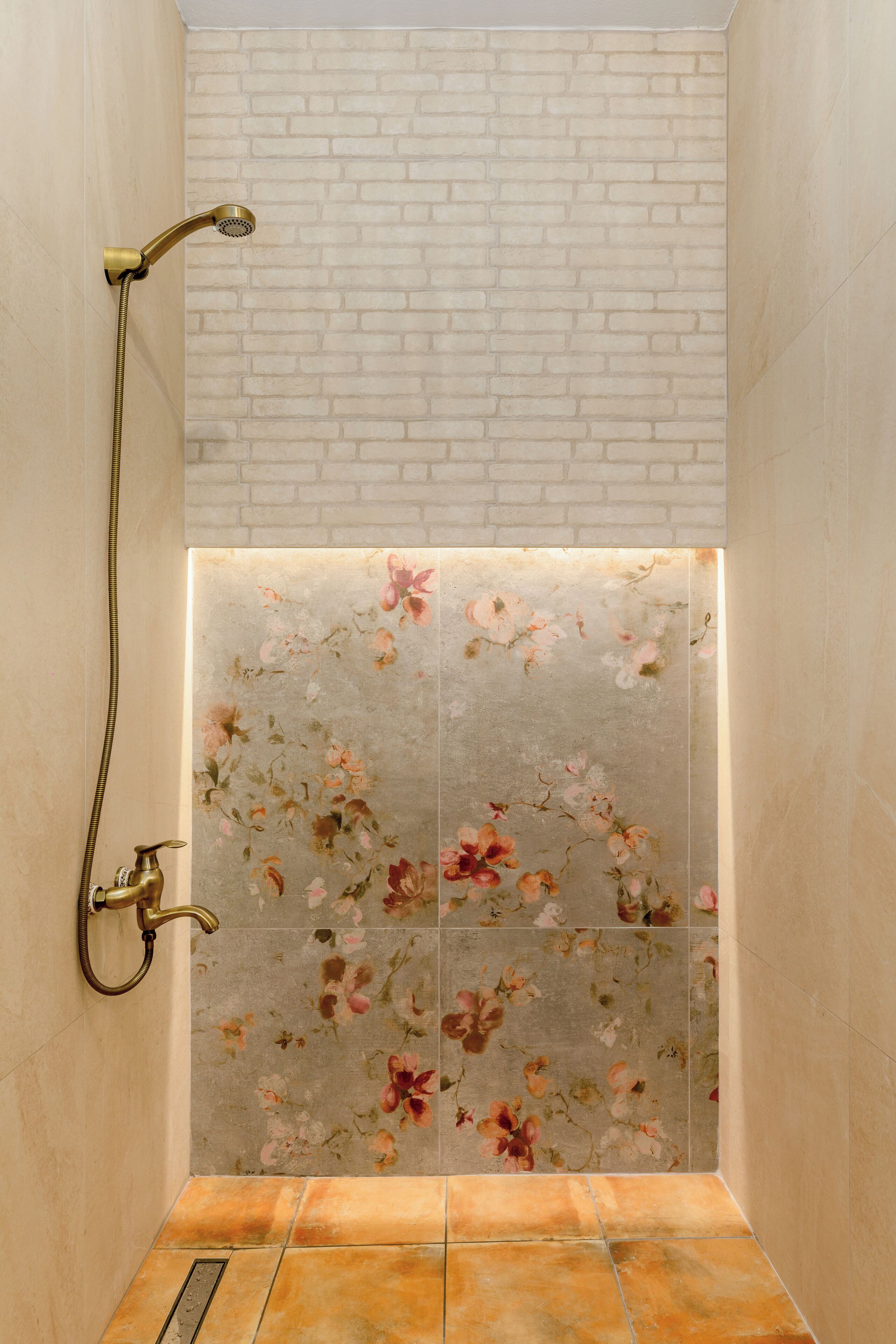 Ducha con pared de ladrillo y azulejos florales.
