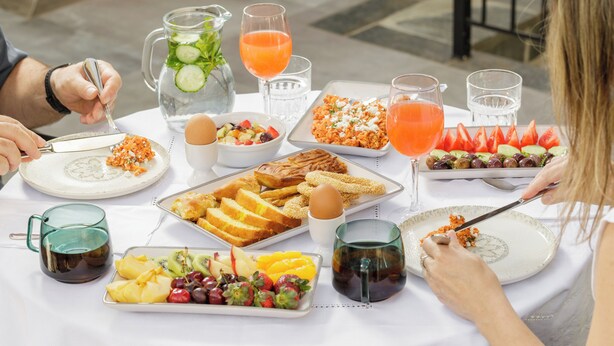 Une table dressée pour le petit-déjeuner, avec différents plats, boissons et ustensiles.