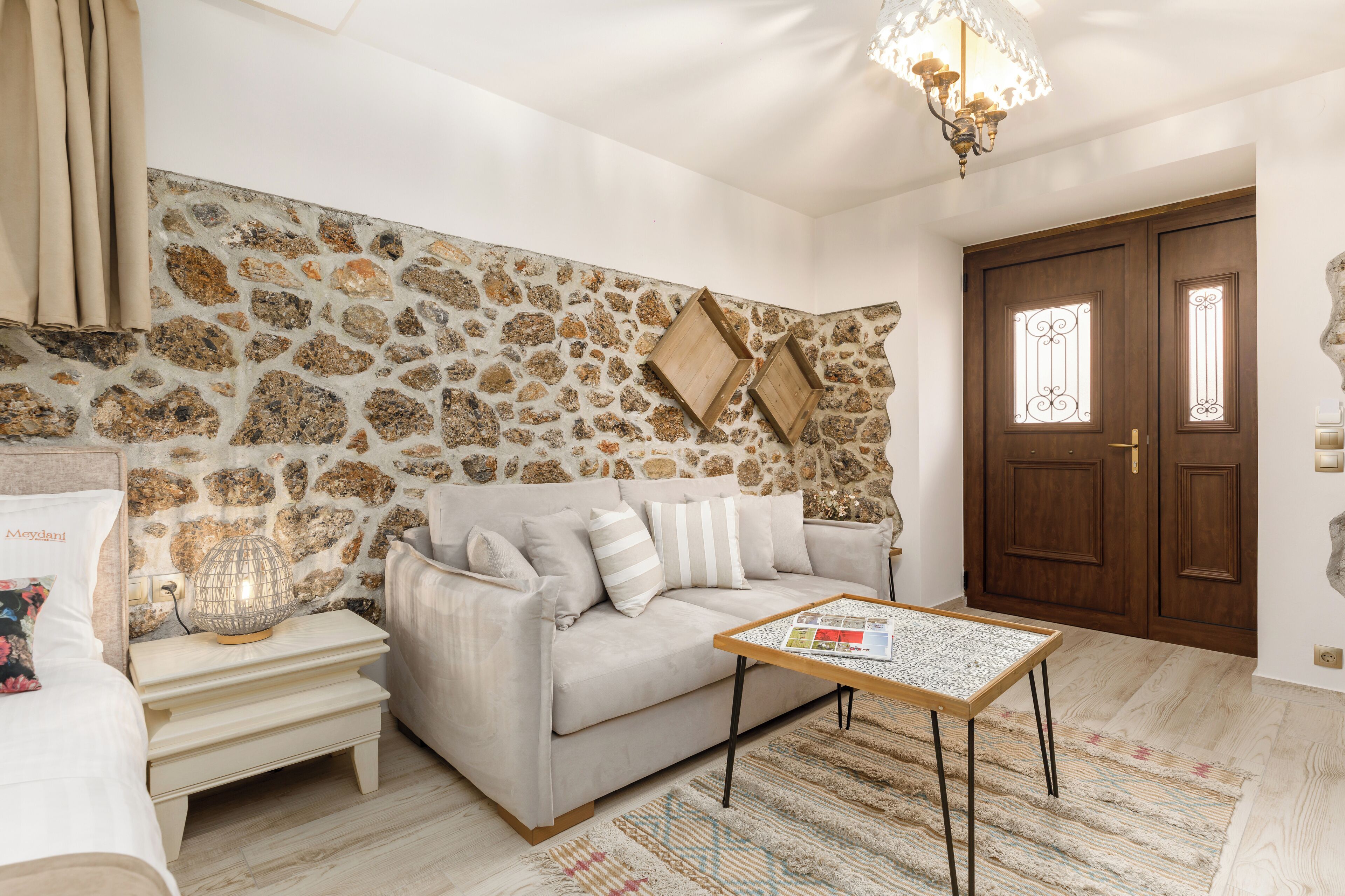 Una sala de estar con pared de piedra, un sofá, una mesa de centro y una puerta con paneles de vidrio decorativos.