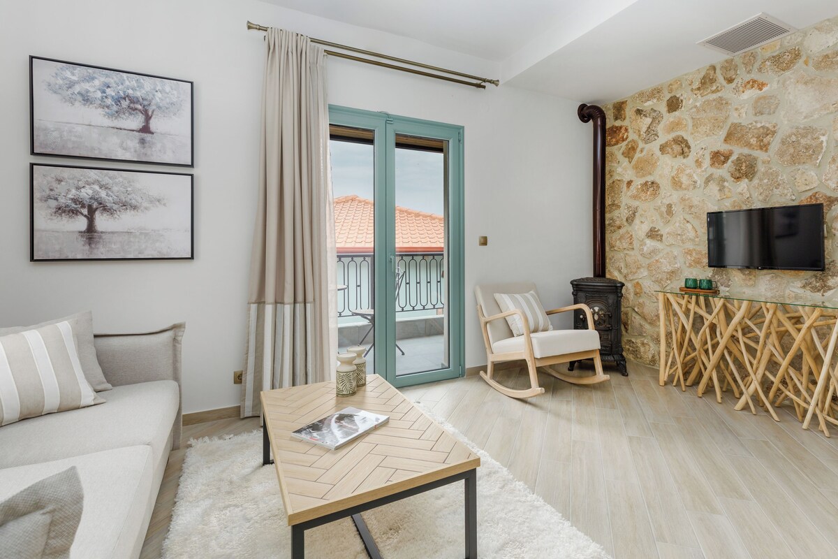 Una sala de estar con sofá, mesa de centro, mecedora, chimenea y pared de piedra.