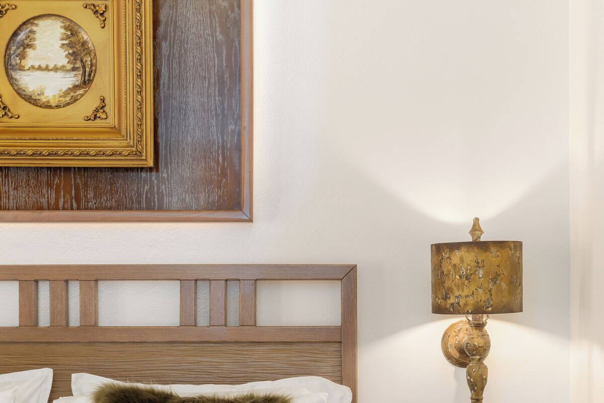 A neatly made bed with a fluffy pillow, a bedside table with a lamp, and a framed picture on the wall.