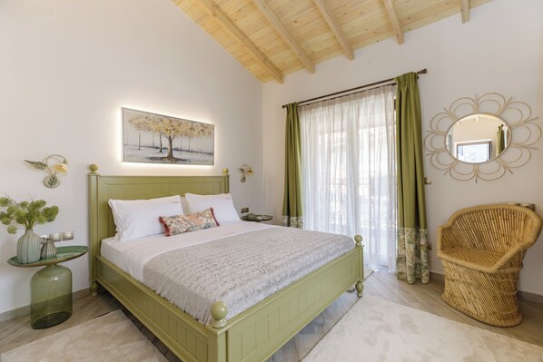 A bedroom with a green bed, a wicker chair, a mirror, and a painting on the wall.