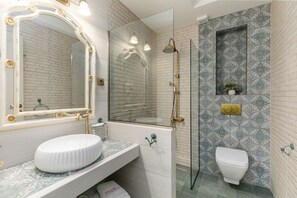 Un baño con lavamanos blanco, un espejo grande con iluminación, ducha e inodoro.
