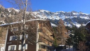 A building with multiple balconies and a view of snow-covered mountains. - Rustic Modern Studio • Ski-in, Ski-out • King Bed (Wengen)