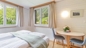 A bedroom with two beds, a small table with chairs, and a window with curtains. - Rustic Modern Studio • Ski-in, Ski-out • King Bed (Wengen)