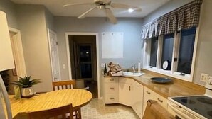 A kitchen with a dining table, chairs, a ceiling fan, cabinets, a stove, and a window with curtains. - 1 mile to beach The Point House (Point Pleasant Beach)