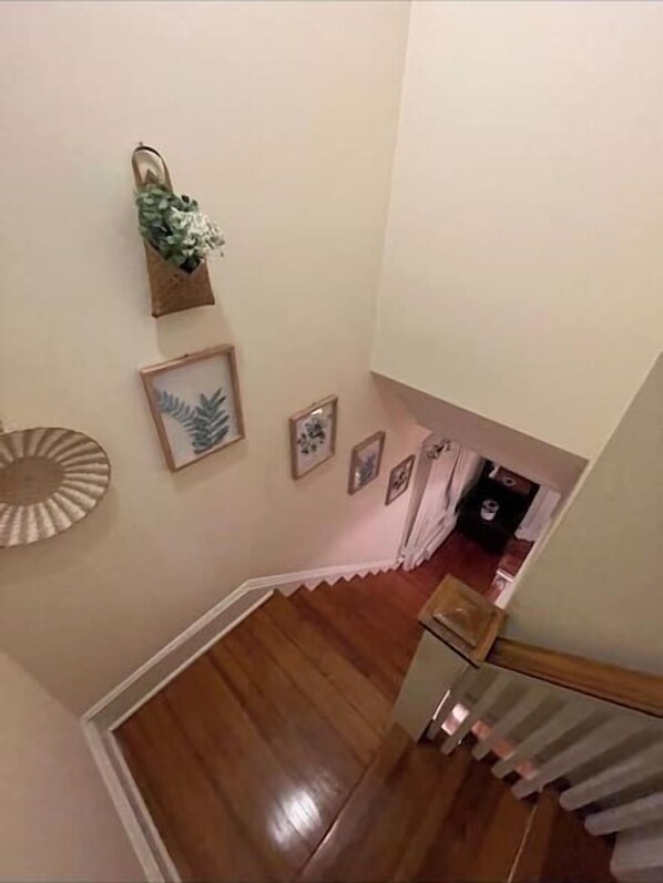 A staircase with wooden flooring leading to a landing. There are framed pictures and a small plant on the wall. - 1 mile to beach The Point House (Point Pleasant Beach)