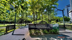 Legazpi-parken, en aktivitetspark med en asfalterad gångväg, träd och en informationsskylt.
