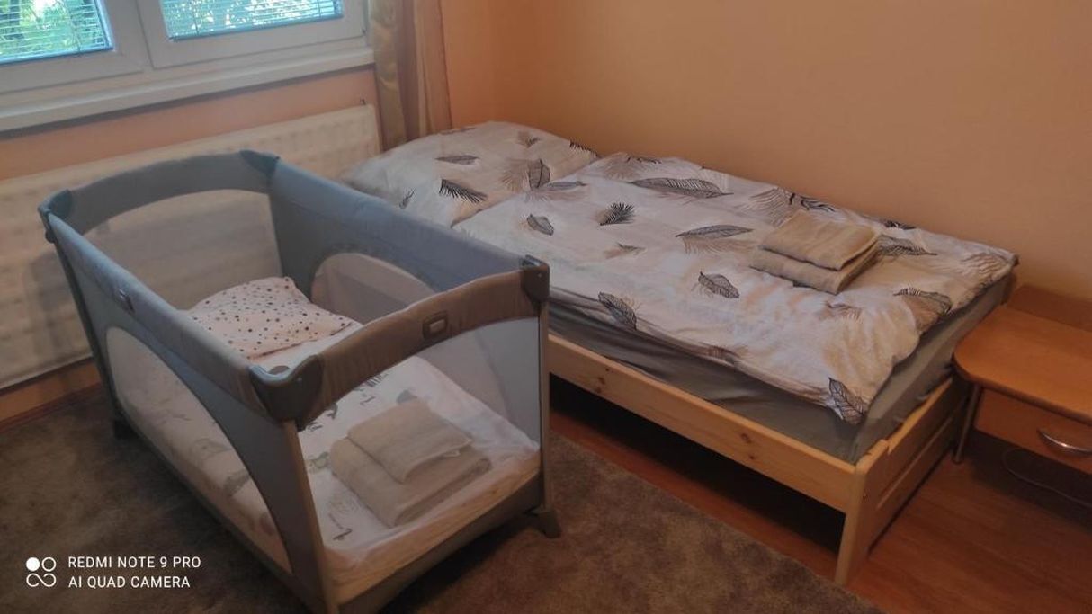 Une pièce avec un petit lit, un berceau et une fenêtre avec des stores.