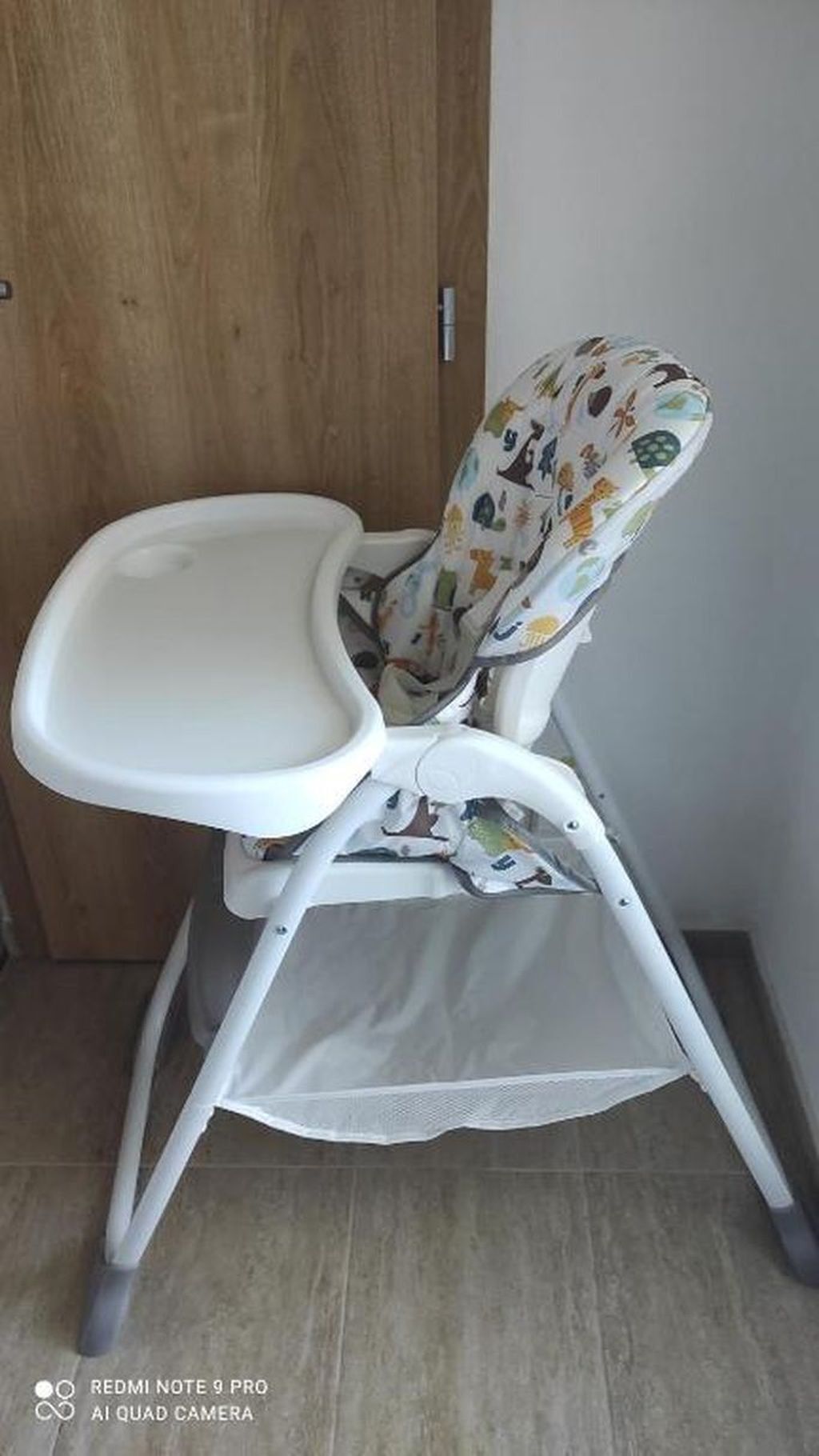 Une chaise haute pour bébé avec un plateau blanc et un siège à motifs.