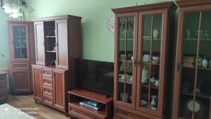 Ein Wohnzimmer mit Holzkästen, einem Fernseher und einer Wanduhr.