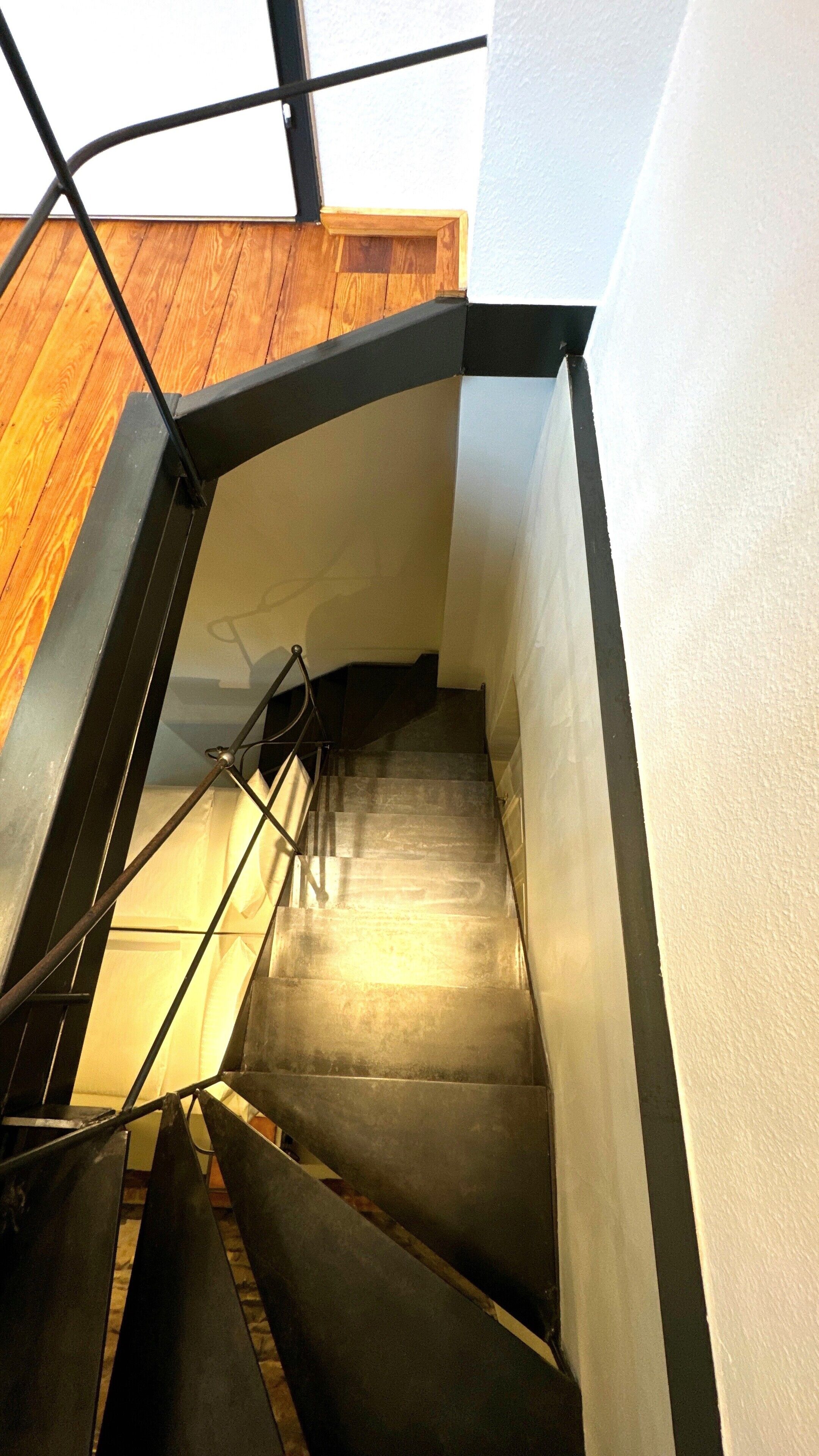 Eine Treppe mit Metallgeländern und Holzstufen, die zu einer höheren Etage führt.