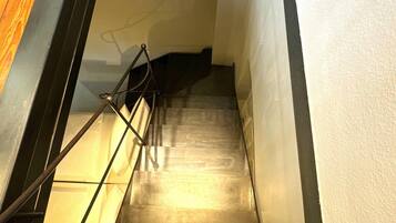 Eine Treppe mit Metallgeländern und Holzstufen, die zu einer höheren Etage führt.
