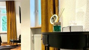 Una sala de estar moderna con una mesa de centro negra, una mesita auxiliar con un jarrón y vistas a una ventana con cortinas.