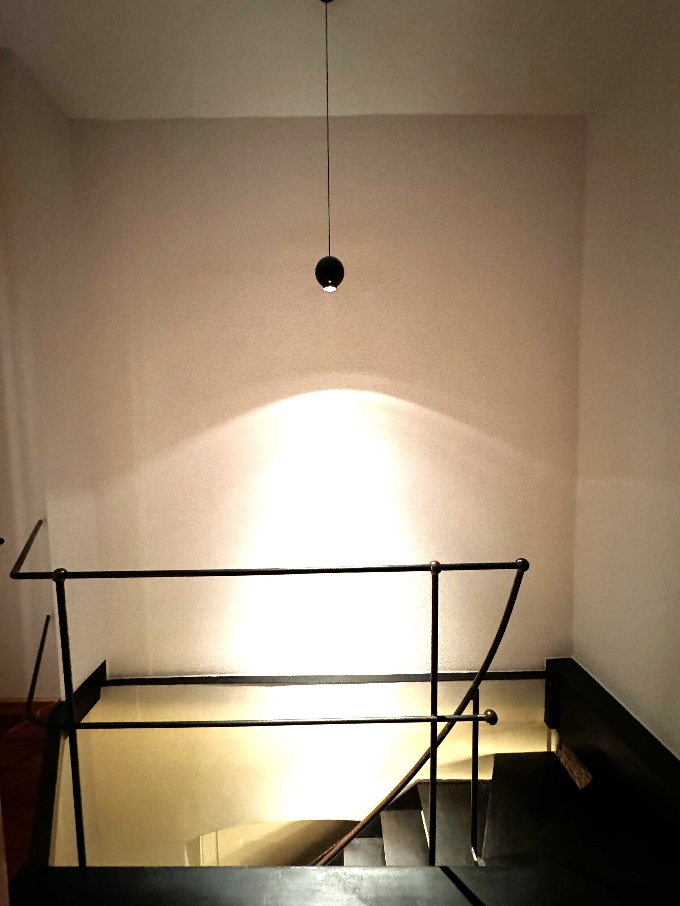 A staircase with a metal railing and a light fixture above.