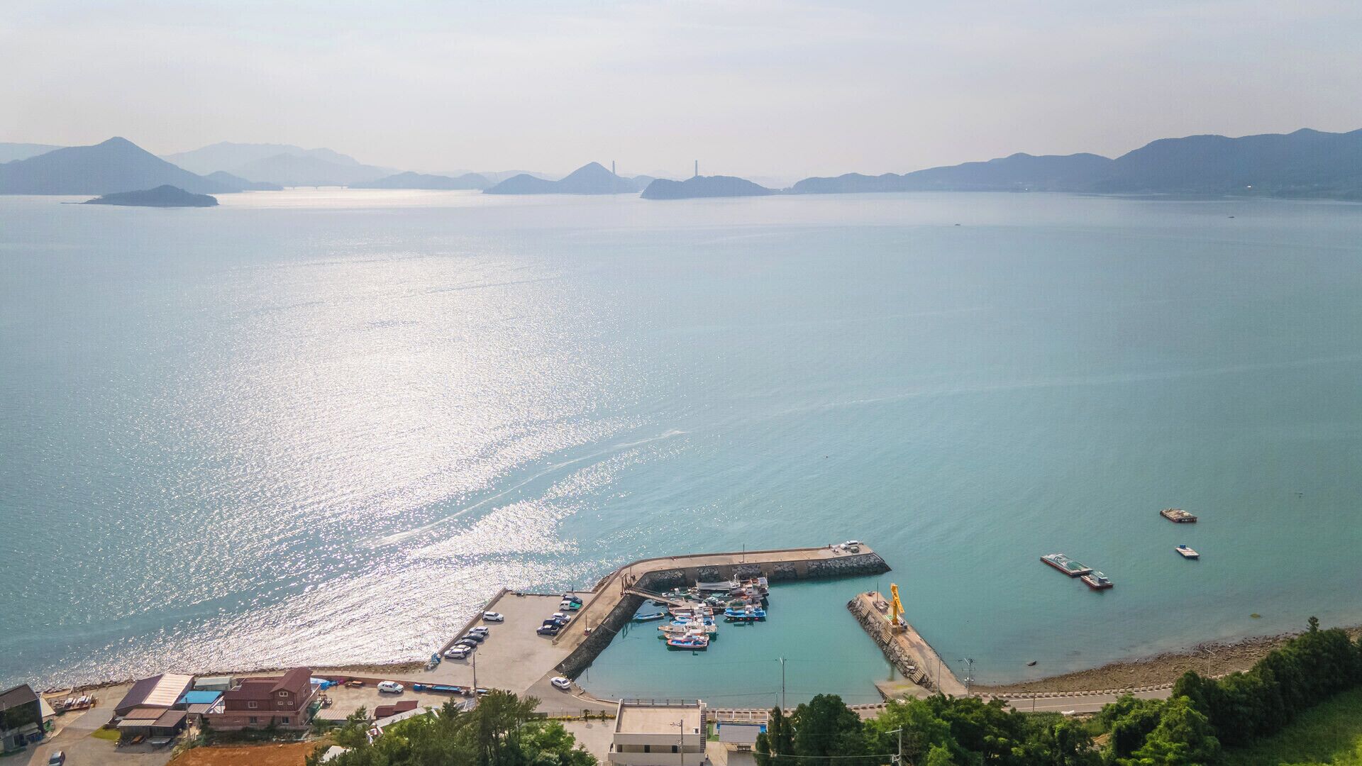 Un puerto costero con barcos amarrados, un muelle y una vista despejada del agua circundante y montañas distantes.