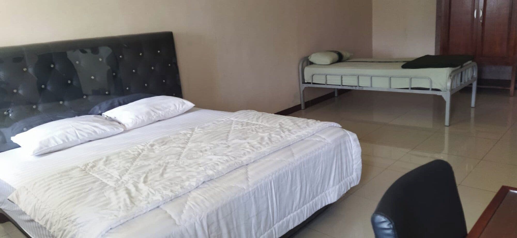 A hotel room with a large bed, a smaller bed, and a desk with a chair.