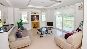 A modern living room with a sofa, a glass coffee table, a TV, and a fireplace. - Beautiful Detached Villa With Private Pool And Stunning Views,Walkable to Town. (Dalanan)