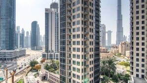 Un immeuble de grande hauteur, doté de nombreux étages et de balcons, entouré d’autres bâtiments imposants et surplombant un ciel dégagé.