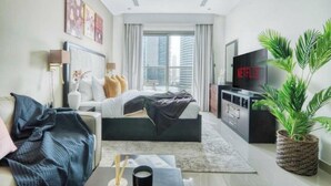 Une chambre d’hôtel moderne équipée d’un lit, d’une télévision, d’un bureau et d’une grande fenêtre.