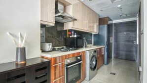Une cuisine moderne dotée d’appareils électroménagers intégrés, de meubles de rangement en bois et d’une porte de couleur sombre.