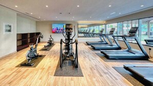 Une salle de sport moderne équipée de tapis de course, de vélos d’appartement et d’appareils elliptiques.