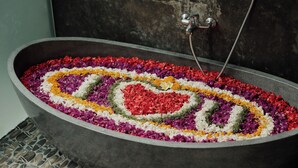 A bathtub filled with colorful flower petals arranged in a heart shape. - Oemah Cinta Ubud Villa (Tegallalang)