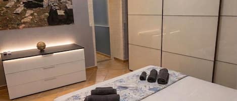 A modern bedroom with a bed, a bedside table with a globe, a wall-mounted artwork, and a large wardrobe.