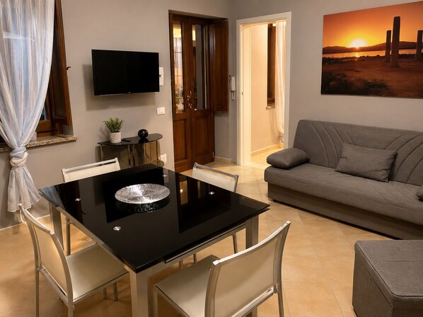 Ein modernes Wohnzimmer mit Esstisch, Sofa, Fernseher und einem Sonnenuntergangsbild.