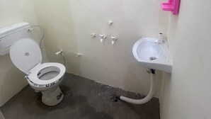 Pieni, yksinkertainen kylpyhuone, jossa on wc, pesuallas ja vaaleanpunainen kaide.