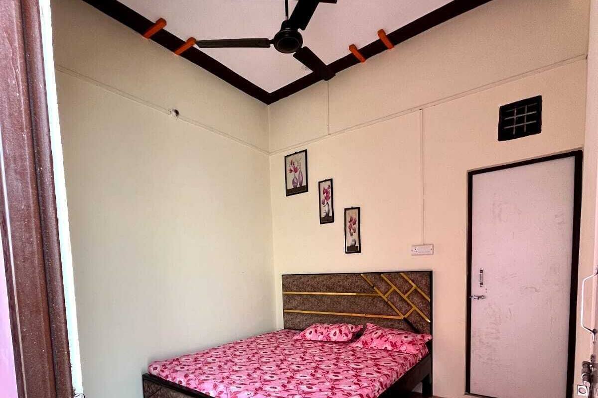 Ein Schlafzimmer mit einem Bett, einem Deckenventilator, einer Tür und einer Wand mit drei gerahmten Bildern.