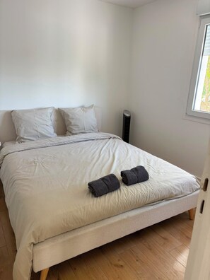Una camera da letto con un letto, cuscini, un comodino e una finestra.