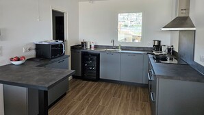 A modern kitchen with a built-in microwave, a dishwasher, and a large window. - Appartement Neuf de 84 m2 Avec Terrasse de 60 m2 vue mer (L'Île-Rousse)
