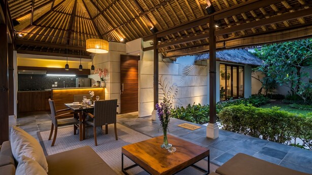 A modern kitchen with a dining area, a wooden ceiling, and a view of a lush garden.