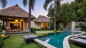 A resort with thatched-roof cottages, a swimming pool, and lush greenery.