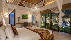 A bedroom with a bed, a desk, and a view of a garden.