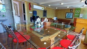 A conference room with a glass table, red chairs, a brown sofa, and a clock on the wall. - Ikraam Inn (Srinagar)