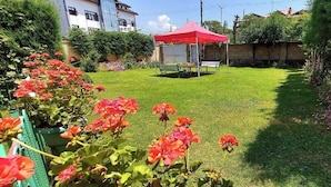 A well-maintained garden with a red tent, lush greenery, and flowering plants. - Ikraam Inn (Srinagar)