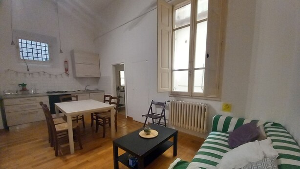 Um espaço compacto com área de jantar, cozinha compacta e sofá com almofadas listradas.