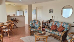 Ein Wohnzimmer mit einer Couch, Sesseln, einem Couchtisch und einem Essbereich mit Tisch und Stühlen.