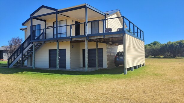 Ein zweistöckiges Haus mit Balkon, Garage und überdachter Veranda.