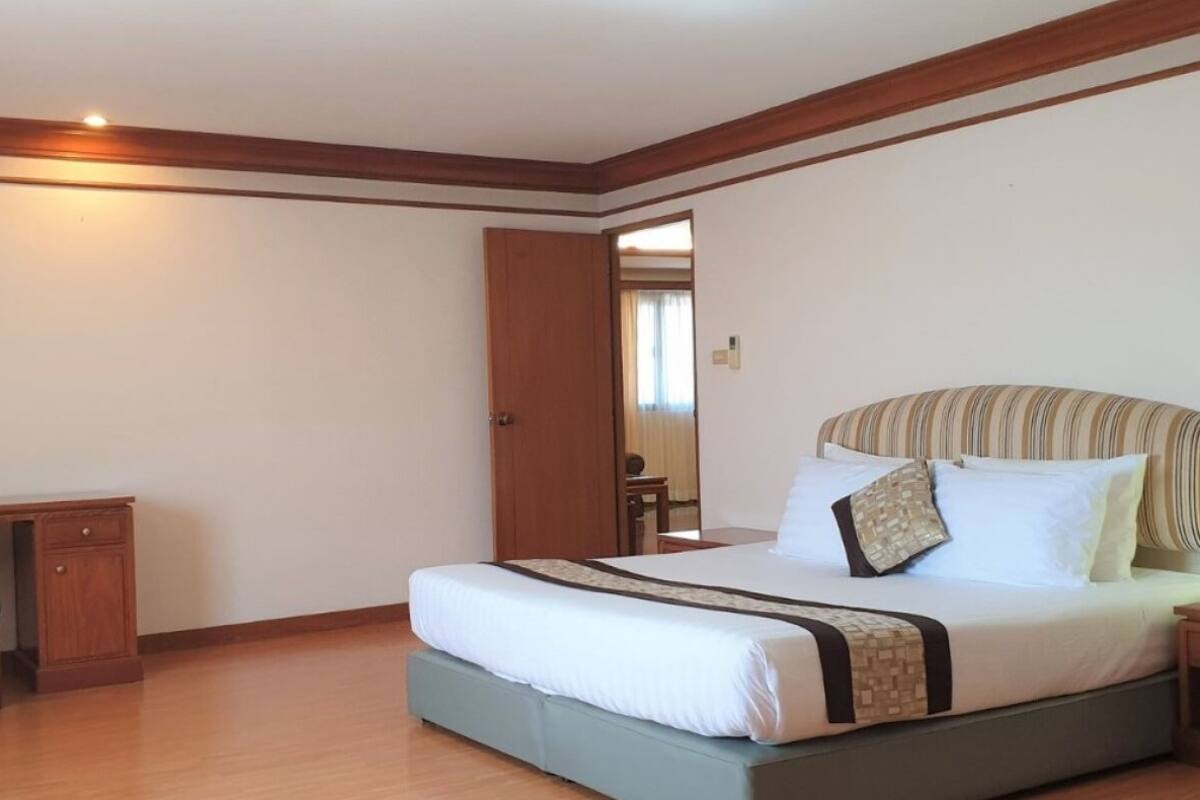A bedroom with a bed, a desk, and a door.