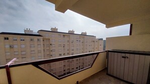 A balcony with a view of adjacent buildings, a metal railing, and a storage cabinet. - Enjoying the beach (Playa de Gandia)