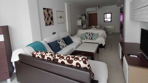 A modern hotel room with a large bed, a sofa, a coffee table, and a TV. - Enjoying the beach (Playa de Gandia)