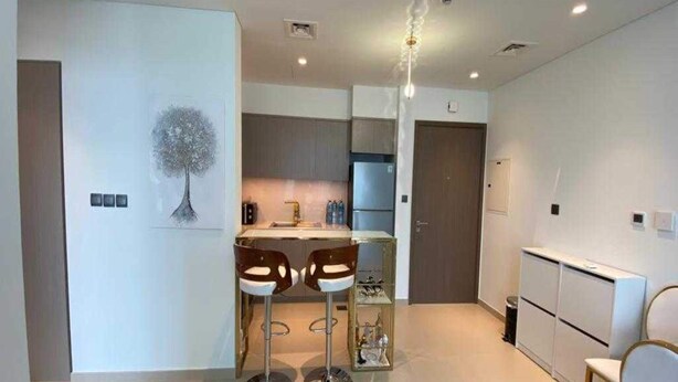 A modern kitchen with a dining area, featuring a central island, bar stools, and a pendant light. - OYO 1194 Home Orion Building 514 (Dubai)